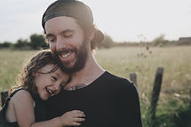 Dad holding his daughter in a field