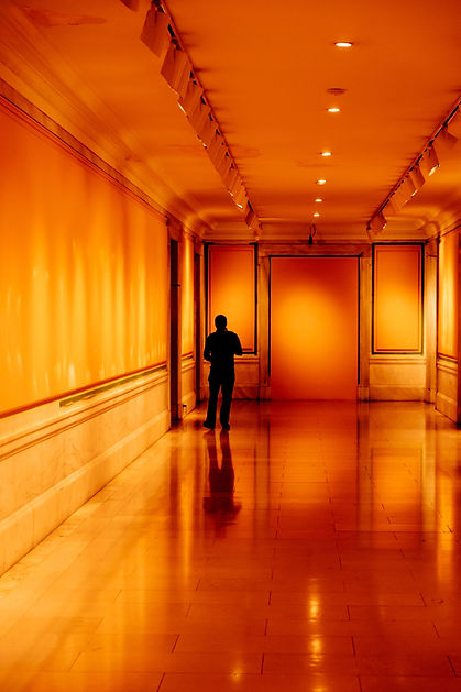 silhouetted person in an empty, amber-lit room