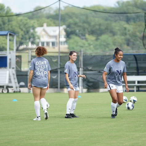 Smiling youth female footballers enjoying a positive training session, demonstrating teamwork and a healthy positive mindset and attitude in football.