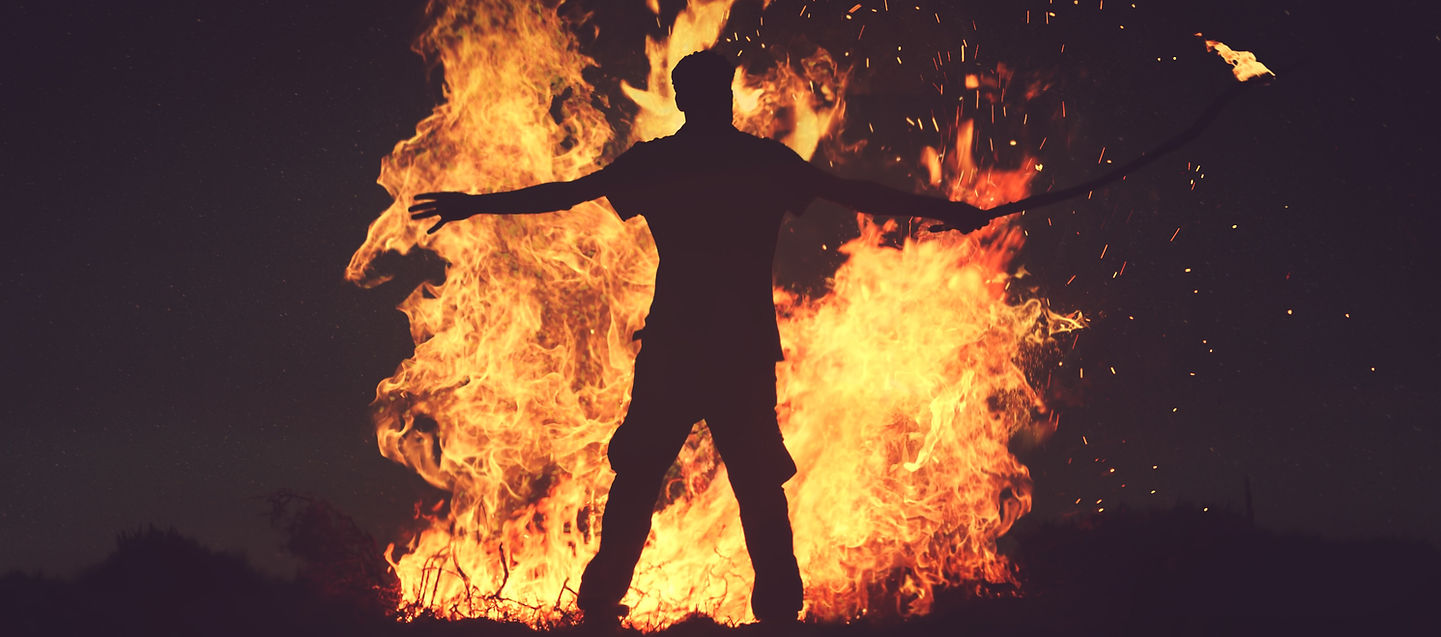 Silhouette of a man standing in front of flames – representing passion, conviction, and burning purpose.