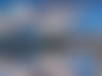 Modern building and arch bridge reflected in a calm river under a dramatic sky. Blue and silver hues dominate the serene urban scene.