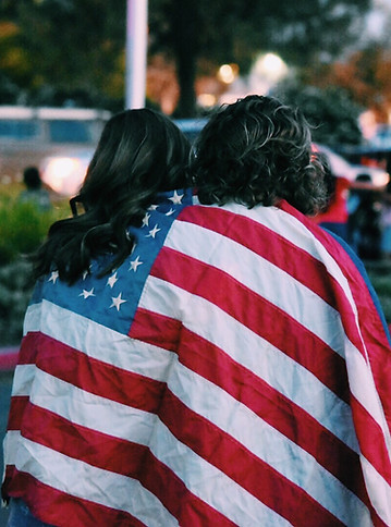 Two women wearing the American flag as a blanket