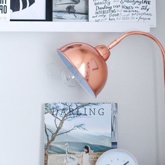 A shelf, a clock, a magazine and a book neatly lined up, evoking a space of culture, symbolising time and knowledge.