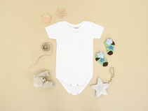 Baby onesie, pacifier, socks and a teddy bear