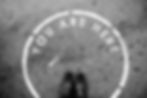 Black shoes on a concrete surface with "You Are Here" written in a white circle. Monochrome image with a straightforward, introspective mood.
