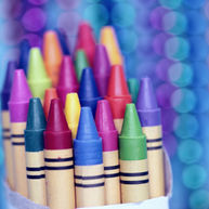Colorful crayons in a box with vibrant blue and purple bokeh in the background, creating a playful and artistic mood.