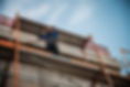 Low-angle view of a construction worker wearing a hard hat working on a metal scaffolding structure against a clear sky