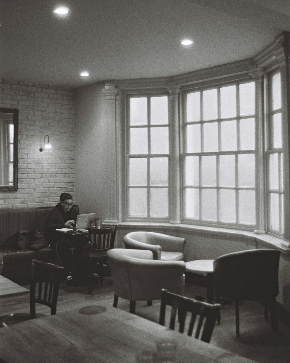 Eine Person in einem Café am Laptop sitzend in schwarz weiß