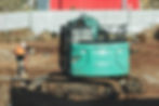 Excavator working on a construction site alongside a builder, illustrating LivFinance’s expertise in providing construction finance for large-scale development projects.