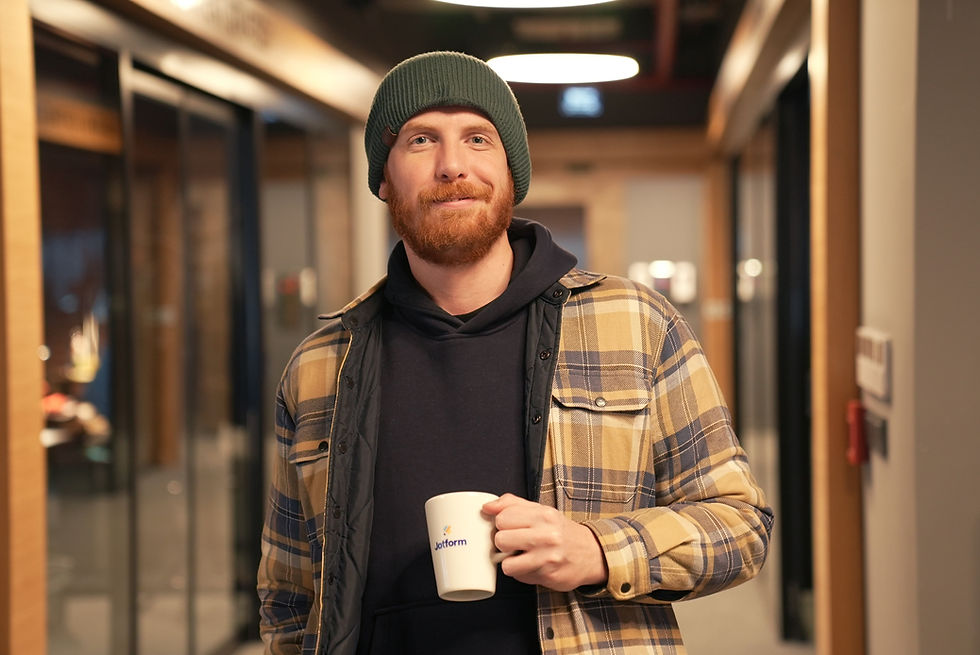 Man in a flannelette shirt and a Bennie holding a cup of coffee maybe sufering poor mental health