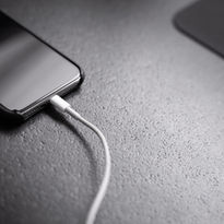 Smartphone plugged into a white charging cable
