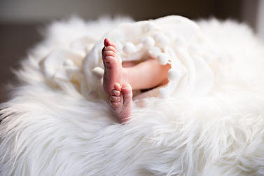 Pieds croisés de bébé enveloppé dans une couverture sur un tapis tout doux