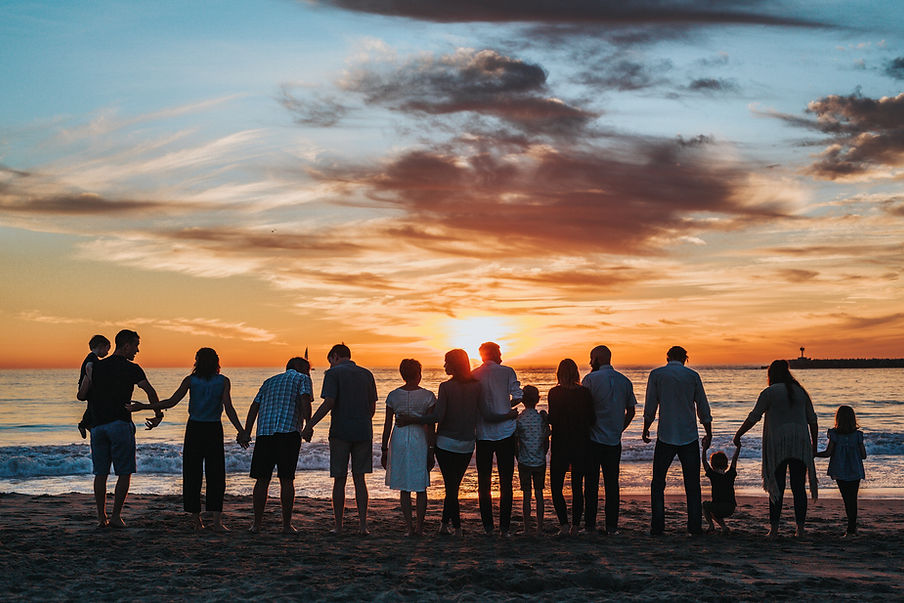 Family standing together on the beach, looking at the ocean | Image by Tyler Nix