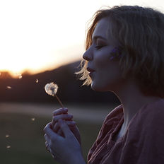 woman blowing on dandilion