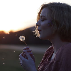 woman blowing on dandilion