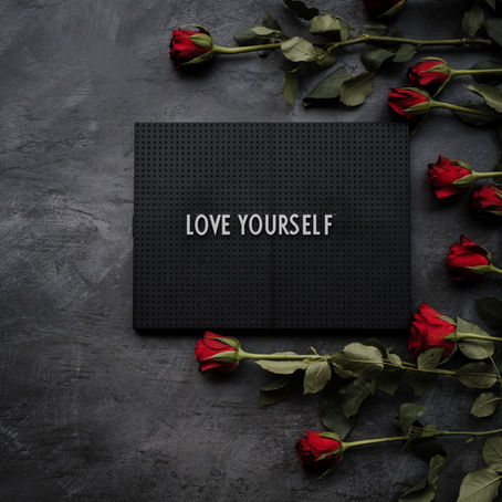 A sign that says love yourself, surrounded by roses.