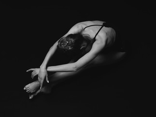 Balletttänzerin in schwarz weiß macht Dehnübungen auf dem Boden