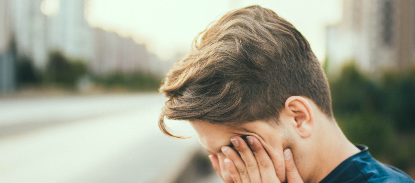 A tired man bowing his head, capturing the reality of pushing through physical fatigue during training or life.