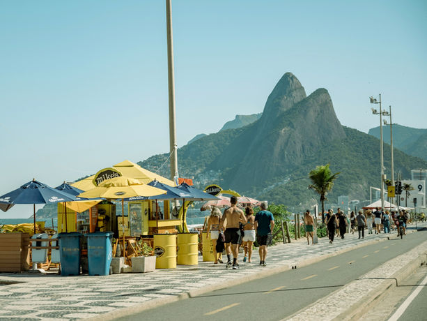 Passeggiata lungo la spiaggia di Ipanema con montagne sullo sfondo.