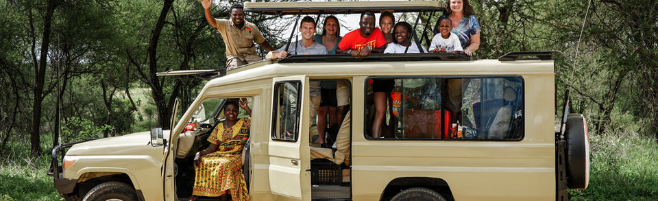 Happy safari guest seated in open safari jeep during Serengeti game drive