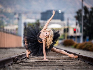 Ballerina im schwarzen Kleid auf Bahngleisschienen