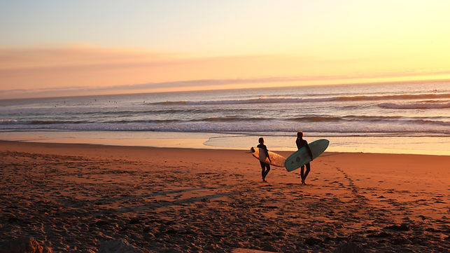 Surfers walking into the sunset at the beach