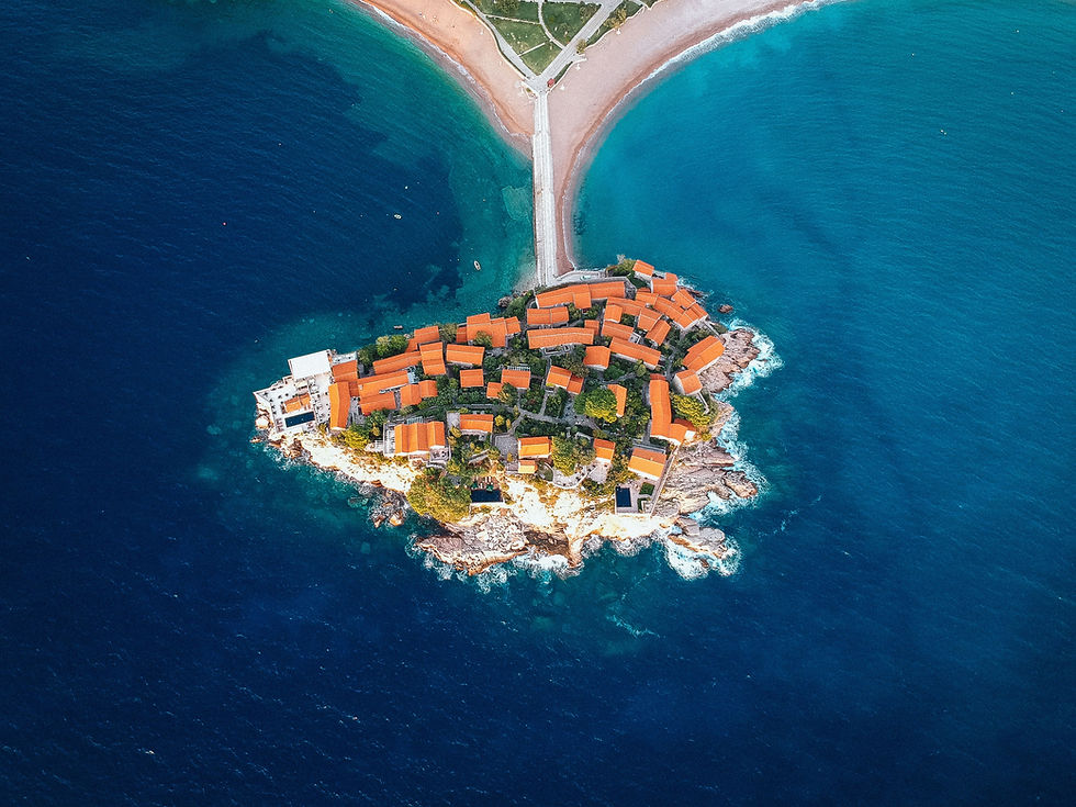 A stunning view of the picturesque island of Sveti Stefan, located in Montenegro, with turquoise waters and red-roofed houses on the rocky peninsula.