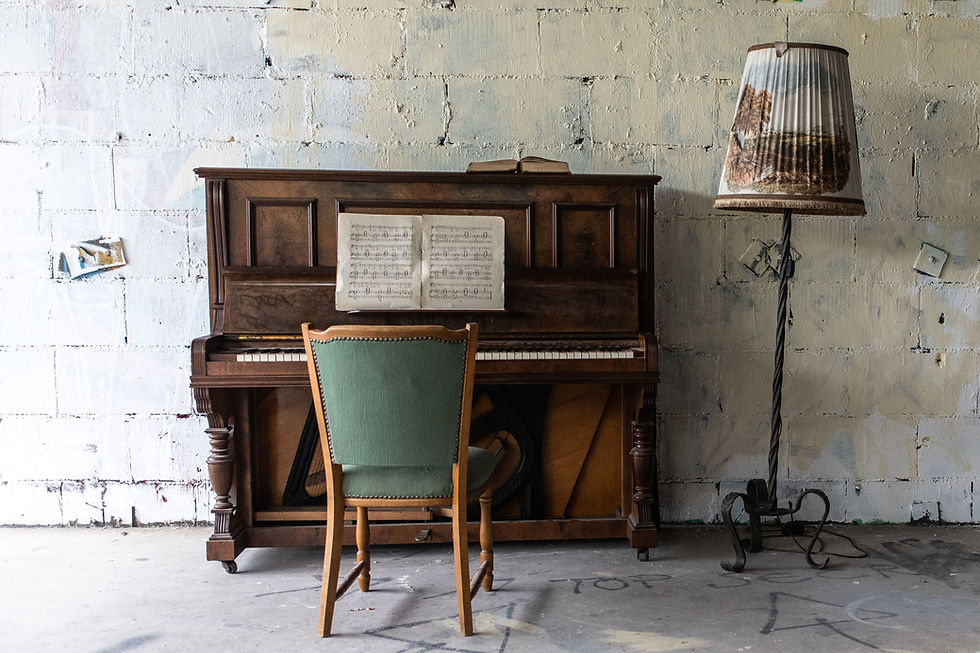 Vintage piano with sheet music, green chair in front, and a floor lamp. Set against a textured, painted wall for a rustic vibe.