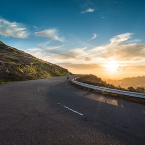 Man running on a winding highway toward sunrise with birds and scenic valley, symbolizing the journey of starting over after divorce