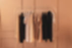 A simple clothing rack with beige, white, and black shirts.