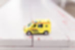 A yellow toy ambulance truck sits on a table. 