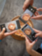 Smartphones taking photos of a pizza pie.