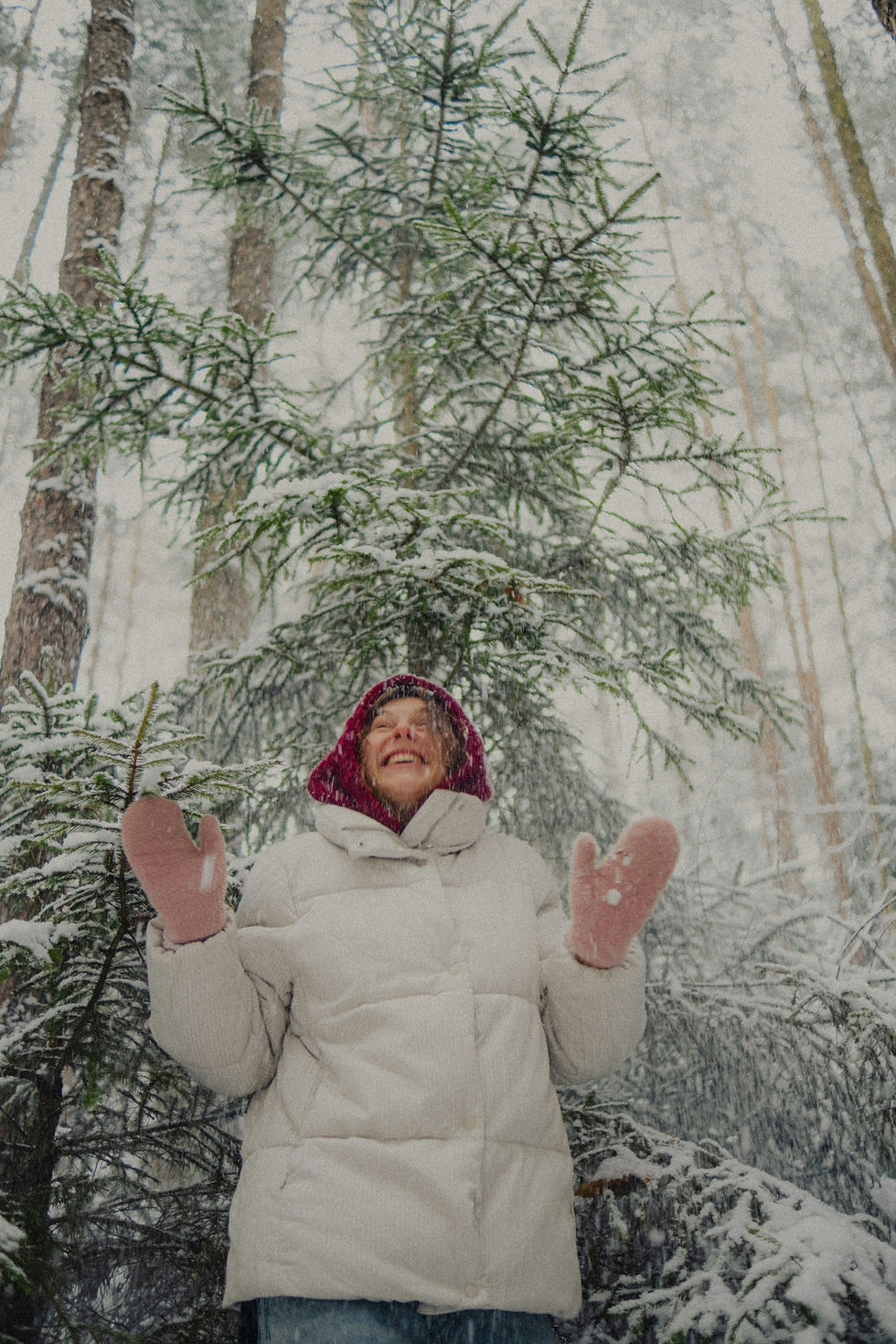 A happy women in a wintery forest during snow fall