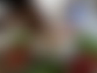 Hand dips a green bean into hummus from a white tray filled with colorful vegetables on a wooden table. Mood is casual and inviting.