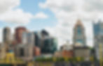 Skyline of a city with tall, varied skyscrapers under a partly cloudy sky. Yellow bridge and "PNC" text visible. Calm atmosphere.
