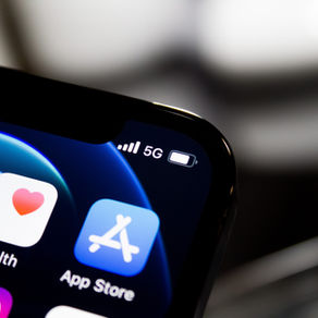 Close-up of a smartphone screen showing app icons, 5G signal, and battery indicator. Background is blurred, with a dark and techy mood.