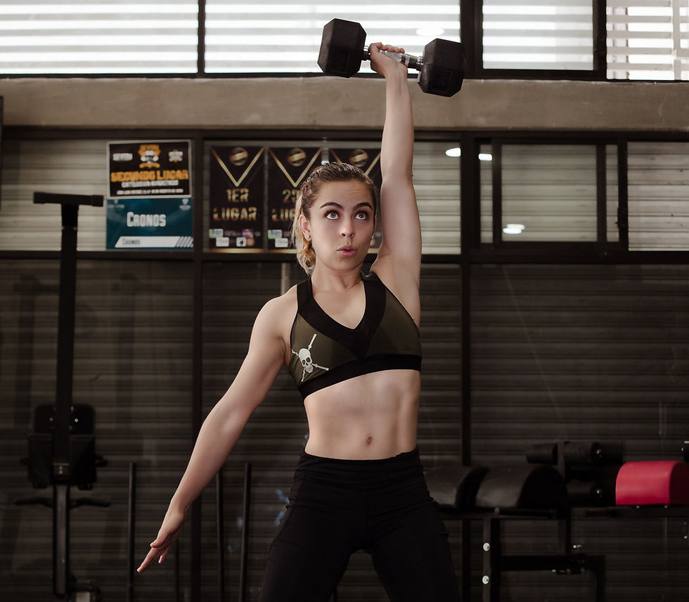 A woman completing a dumbbell emom workout. She is performing the single arm snatch with a dumbbell.