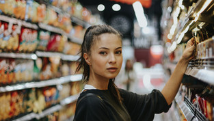 Frau sucht Produkte im Regal