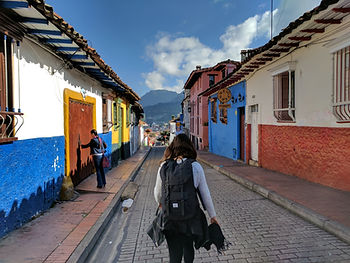 A young backpacker walking down a street in a colonial latin american town.