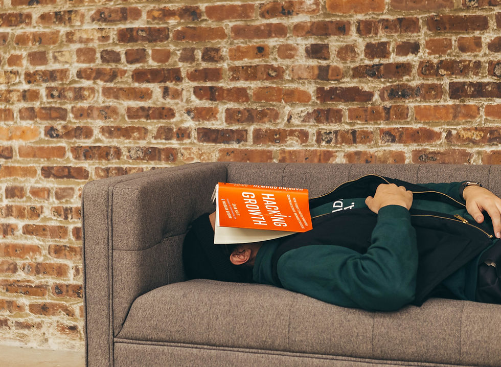 man sleeping on the sofa with an orange book on his face