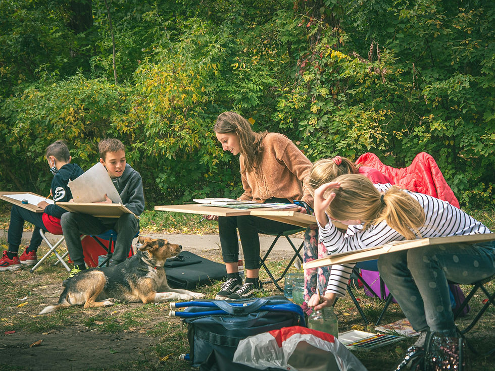 Kids sitting outdoors, drawing on boards, surrounded by green foliage in Costa Rica. A dog lies on the ground. Relaxed atmosphere with vibrant colors.