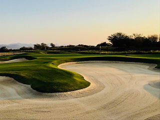 A large sand trap at a golf course positioned just before the green.