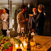 Photo of two groups of people standing with glasses of wine in hand at an event