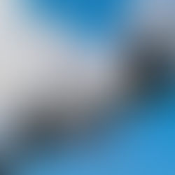 Traffic cameras and lights on a metal pole against a blue sky with clouds. Green light visible, with a calm, clear atmosphere.