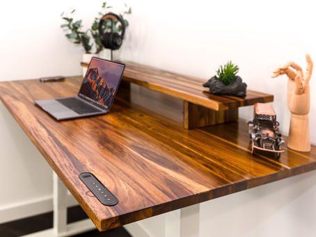 Wooden desk with open laptop showing mountain wallpaper, potted plant, headphones, toy car, wooden hand, and minimal decor. Modern vibe.