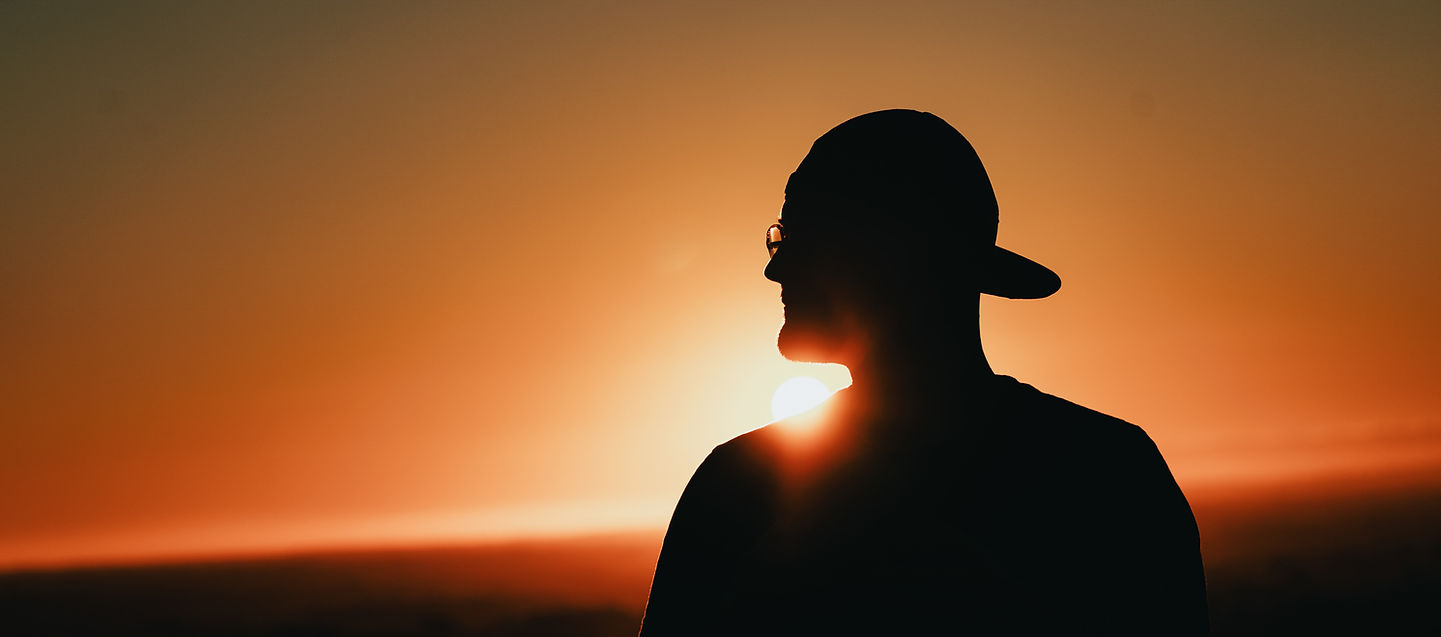Man standing in front of sunset, symbolising inner strength and identity.