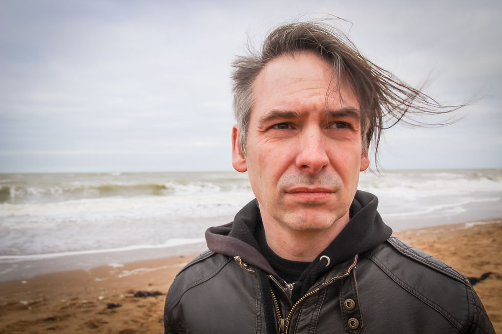 white male close up in casual clothes in front of tide on beach