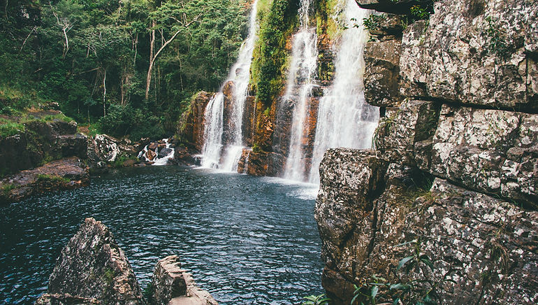 A waterfall flows over rocks into a blue pool at Chapada dos Veadeiros