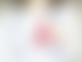 A doctor wearing a her coat and a stethoscope holding a red ribbon symbolizing HIV.