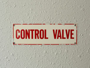 Red-and-white CONTROL VALVE sign mounted on a textured white wall.